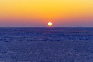 prachtige zonsondergang over het ijzige oppervlak van de zee. foto