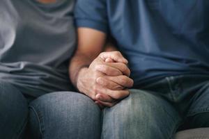 close-up van Aziatische volwassen paar zittend op de bank. vrouw en man hand in hand met geluk en vrolijk. liefde, veiligheid en verzekering familie concept foto