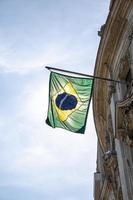 braziliaanse vlag. Braziliaanse vlag op een paal voor het huis. nationale vlag van brazilië zwaaiend op een huis dat aan een paal op een voordeur van een gebouw hangt. foto