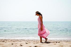 mooie vrouw met lange roze jurk op een tropisch strand foto