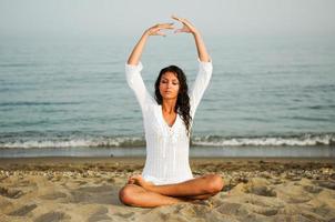 mooie vrouw die yoga doet op het strand foto