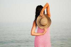 mooie vrouw met lange roze jurk op een tropisch strand foto
