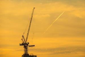 zonsondergang en silhouet van de kraan in werking foto