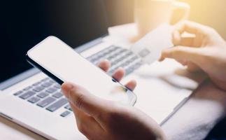 vrouw met smartphone en op zoek naar creditcard voor mobiel bankieren. foto