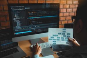 achteruitkijkspiegel van de softwareontwikkelaar werkt aan een computertoetsenbord en analyseert de code die in het programma op de computer is geschreven. foto