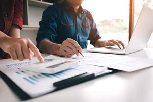 zakenmensen die samen aan een bureau werken en een analysegesprek voeren over samenvattende begrotingsfinanciën en het gebruik van een laptop die een notitierapport maakt. foto