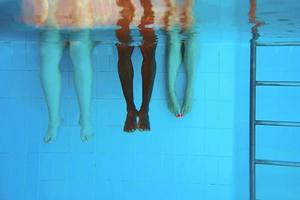 benen van Afro-Amerikaanse man met blanke vrienden in zwembad onder water. zomer. vakantie, internationaal en sportconcept. foto