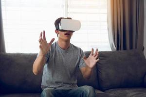 jonge aziatische man met een virtual reality-bril in de woonkamer voor het bewonderen van virtual reality. foto