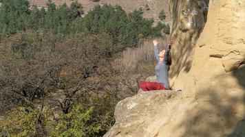 vrouw met gesloten ogen en opgeheven armen zittend op een berg in lotushouding in meditatie op een herfstdag foto