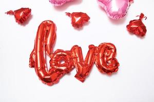 feestelijke achtergrond voor Valentijnsdag van folie ballonnen vorm hart en liefde woord op witte achtergrond foto