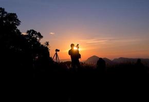 fotograaf staat bij zonsondergang foto