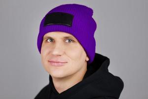 hipster in paarse hoed en hoodie op grijze achtergrond foto