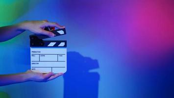 de hand houdt een lege filmklapper vast op een gekleurde achtergrond in de studio foto