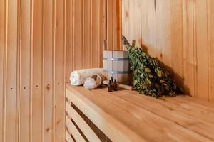 traditioneel oud russisch badhuis spa concept. interieur details Finse sauna stoomkamer met traditionele sauna accessoires set wastafel berken bezem handdoek aroma olie. ontspannen land dorp bad concept. foto