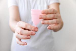 vrouw hand met roze menstruatie cup geïsoleerd op een witte achtergrond. vrouw moderne alternatieve eco gynaecologische hygiëne in menstruatieperiode. container voor bloed in de hand van het meisje. foto
