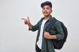 knappe Indiase college jongen wijzend met de hand op een witte achtergrond. foto
