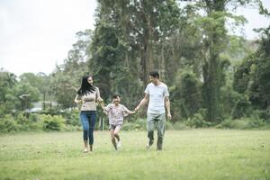 gelukkige ouders en hun dochter wandelen in het park, gelukkig familieconcept. foto