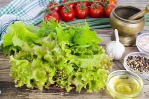 groene salade ingrediënten biologische sla, cherrytomaatjes, kruiden en olijfolie op houten achtergrond. foto