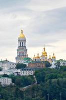 de klokkentoren van de pechersk lavra en de gouden koepels van het klooster op de hellingen van de heuvels van Kiev op een bewolkte zomerdag. foto