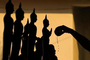 silhouet van boeddha die water naar boeddhabeeld giet in de songkran-festivaltraditie van thailand foto