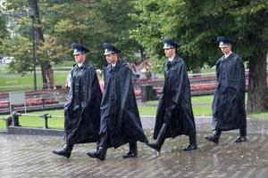vier Russische soldaten steken een park in moskou over onder zware regen. mensen op de achtergrond die naar hen kijken foto