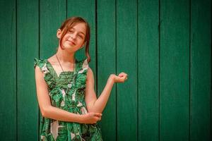 tiener meisje portret in een jurk op een groene achtergrond. meisje van 10 of 11 jaar oud op een zomerse dag. foto