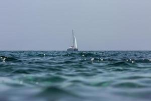 witte zeilboot catamaran op oceaan in de buurt van strand. foto