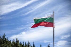 Bulgaarse nationale vlag op een paal tegen zijdeachtige wolken. foto