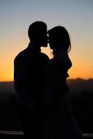 silhouet van bruid en bruidegom op zonsondergangachtergrond foto