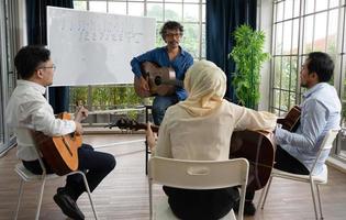 muziekleraar die gitaar lesgeeft aan studenten in de klas foto