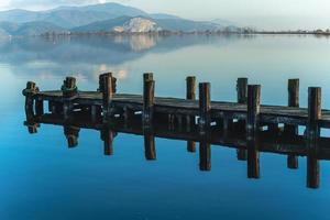 houten steiger weerspiegeld op het water van een blauw meer massaciuccoli meer lucca foto