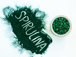 groene hawaiiaanse spirulina in poeder met inscriptie spirulina op lichte witte achtergrond. superfood, gezonde levensstijl, concept voor gezonde supplementen foto