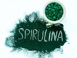 groene hawaiiaanse spirulina in poeder met inscriptie spirulina op lichte witte achtergrond. superfood, gezonde levensstijl, concept voor gezonde supplementen foto