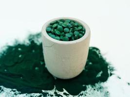 groene hawaiiaanse spirulina in eetlepels pillen en poeder op lichte witte achtergrond. superfood, gezonde levensstijl, concept voor gezonde supplementen foto