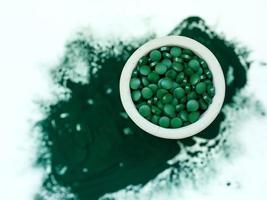 groene hawaiiaanse spirulina in eetlepels pillen en poeder op lichte witte achtergrond. superfood, gezonde levensstijl, concept voor gezonde supplementen foto