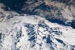 het uitzicht vanuit het vliegtuig op de besneeuwde toppen van de alpenbergen foto