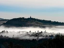 kerk op de heuvel en mooie witte mist met zonnestralen, Elzas foto