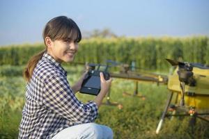 jonge slimme boer die drones bestuurt die kunstmest en pesticiden over landbouwgrond sproeien, geavanceerde technologische innovaties en slimme landbouw foto