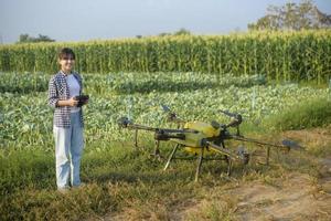 jonge slimme boer die drones bestuurt die kunstmest en pesticiden over landbouwgrond sproeien, geavanceerde technologische innovaties en slimme landbouw foto