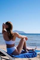 fit sexy aantrekkelijke vrouw liggend op het strand zonnebaden foto