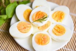 eieren ontbijt, verse eieren menu eten gekookte eieren in een witte plaat versierd met bladeren groene dille achtergrond, in tweeën gesneden eidooiers voor het koken van gezond eten foto