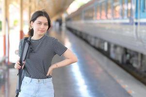 een europese tiener met rugzak die op het treinstation staat en naar de camera kijkt. foto