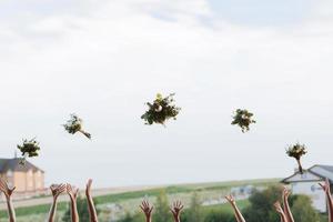 bruid en bruidsmeisjes die boeketten in de lucht overgeven, zonnige huwelijksreceptie. ruimte voor tekst. vreugdevol moment. huwelijksmorgen foto