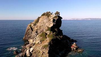 luchtfoto drone uitzicht op pittoreske kapel van sint john gebouwd op de beroemde van mama mia film klif, skopelos eiland, sporades, griekenland. zonsondergang geschoten. foto