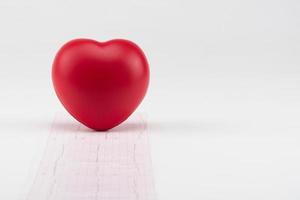 speelgoed hart op elektrocardiogram achtergrond. begrip gezondheidszorg. cardiologie - zorg voor het hart foto