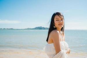 mooie jonge aziatische vrouw gelukkig ontspannen wandelen op het strand in de buurt van zee. levensstijl vrouwen reizen op strand concept. foto