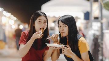 Aziatische jonge vrouwenvrienden reizen in bangkok, thailand, mooie vrouwen voelen zich gelukkig wandelen en eten pad thai op de khao san-weg. vrouwen reizen eten straatvoedsel in thailand concept. foto