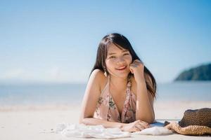 mooie jonge Aziatische vrouw liggend op het strand gelukkig ontspannen in de buurt van zee. levensstijl vrouwen reizen op strand concept. foto