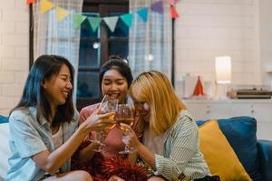 groep aziatische vrouwen feest thuis, vrouwelijke cocktail drinken praten met grappig samen op de bank in de woonkamer in de nacht. tiener jonge vriend speelspel, vriendschap, vier vakantieconcept. foto