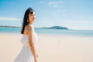 mooie jonge aziatische vrouw gelukkig ontspannen wandelen op het strand in de buurt van zee. levensstijl vrouwen reizen op strand concept. foto